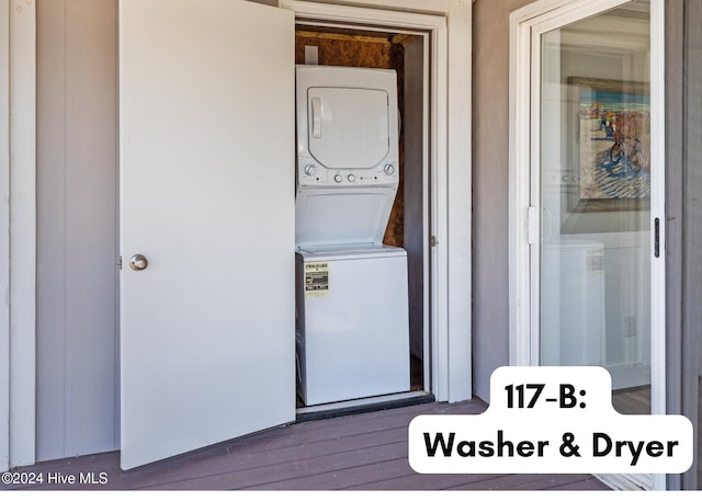 clothes washing area with stacked washer and dryer and hardwood / wood-style flooring