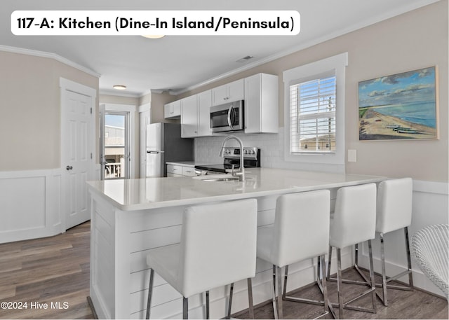 kitchen featuring ornamental molding, light countertops, appliances with stainless steel finishes, and wood finished floors