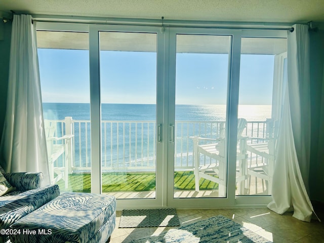 doorway to outside featuring light tile patterned floors, a water view, and a wealth of natural light