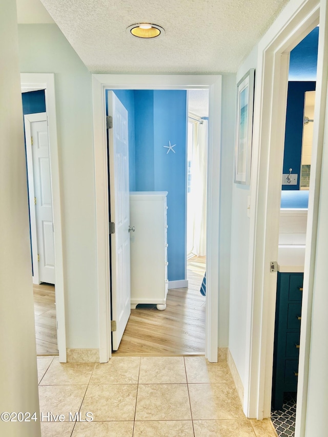 hall with a textured ceiling and light hardwood / wood-style floors