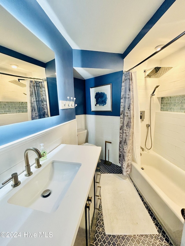 full bathroom with tile patterned flooring, toilet, shower / tub combo with curtain, vanity, and tile walls