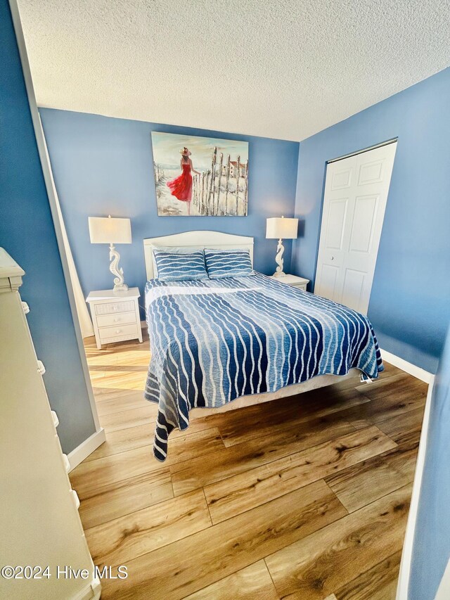 bedroom featuring a closet, wood-type flooring, and a textured ceiling