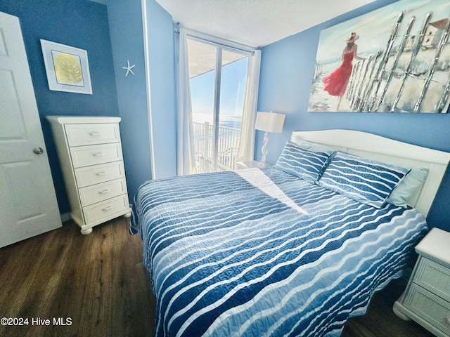 bedroom featuring access to outside, dark hardwood / wood-style flooring, and a textured ceiling