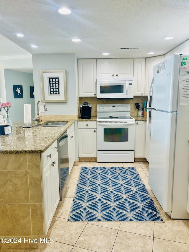 kitchen with white appliances, white cabinets, light stone countertops, light tile patterned floors, and tasteful backsplash