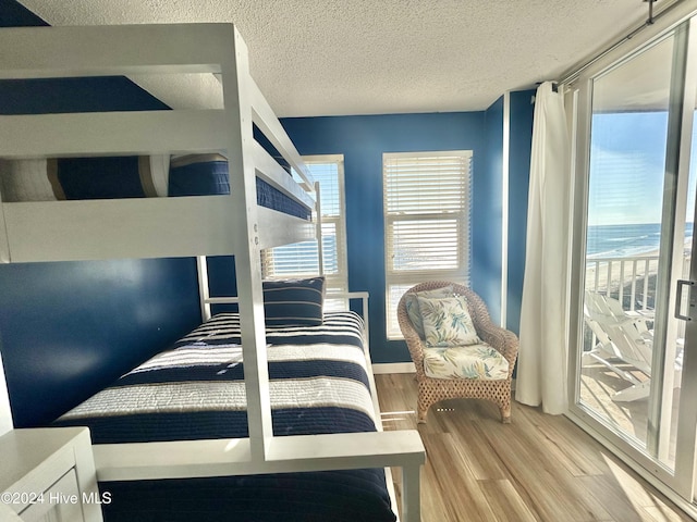 bedroom featuring a water view, wood-type flooring, and a textured ceiling