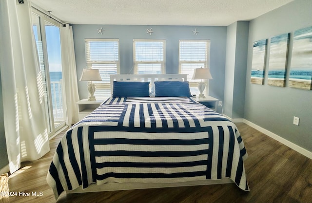 bedroom featuring hardwood / wood-style floors, a textured ceiling, and a water view