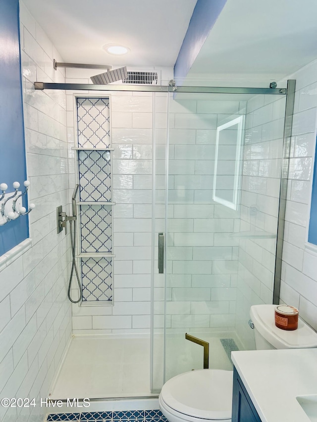 bathroom with vanity, tile patterned floors, toilet, tile walls, and an enclosed shower