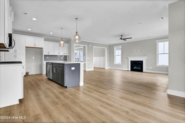 kitchen with stainless steel appliances, light hardwood / wood-style flooring, decorative light fixtures, a center island with sink, and white cabinets