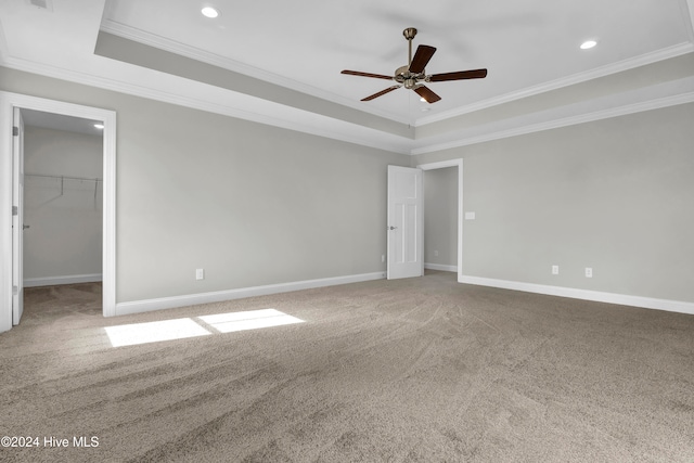 unfurnished bedroom with ceiling fan, a spacious closet, crown molding, and carpet floors