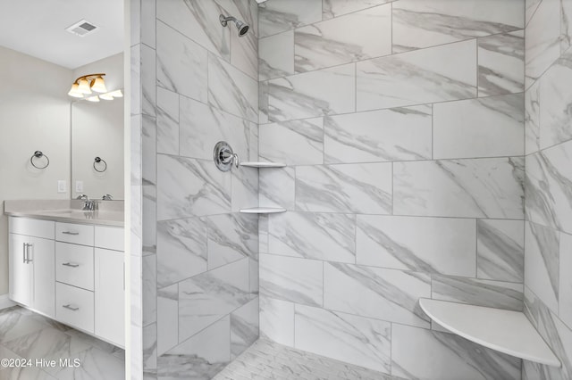 bathroom with a tile shower and vanity