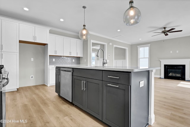 kitchen featuring pendant lighting, dishwasher, white cabinets, light hardwood / wood-style floors, and an island with sink