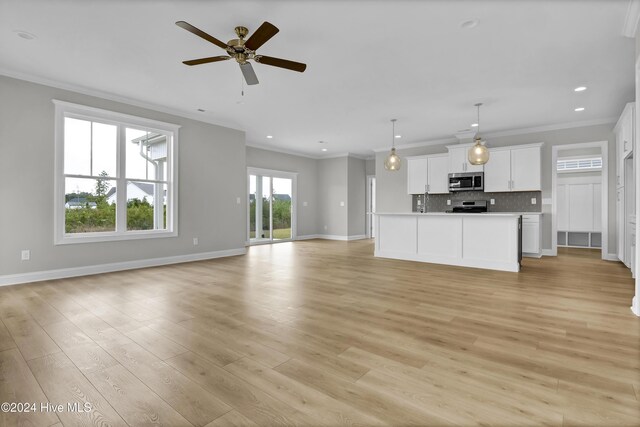 2765 Longleaf Pine Cir, Leland, NC 28451 - unfurnished living room featuring crown molding, recessed lighting, light wood-type flooring, and ceiling fan