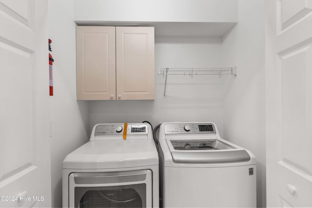 washroom with washer and dryer and cabinets