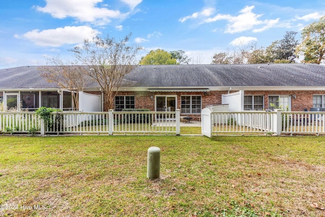 back of house featuring a sunroom and a lawn