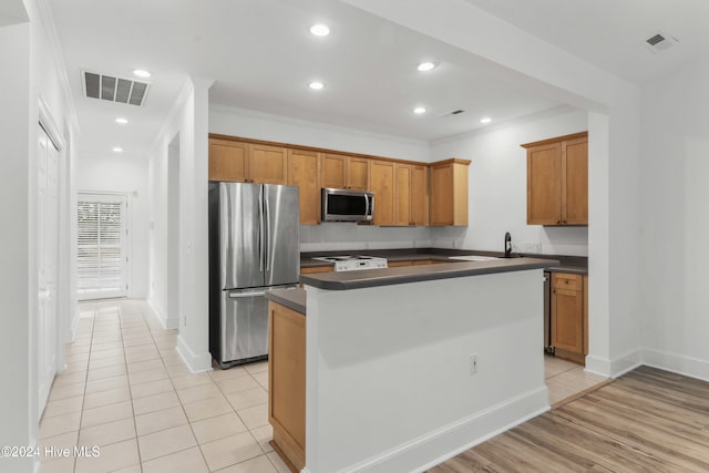 kitchen featuring a center island, ornamental molding, appliances with stainless steel finishes, and light hardwood / wood-style flooring