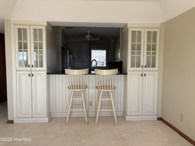 bar featuring ceiling fan, light colored carpet, stainless steel refrigerator, and vaulted ceiling