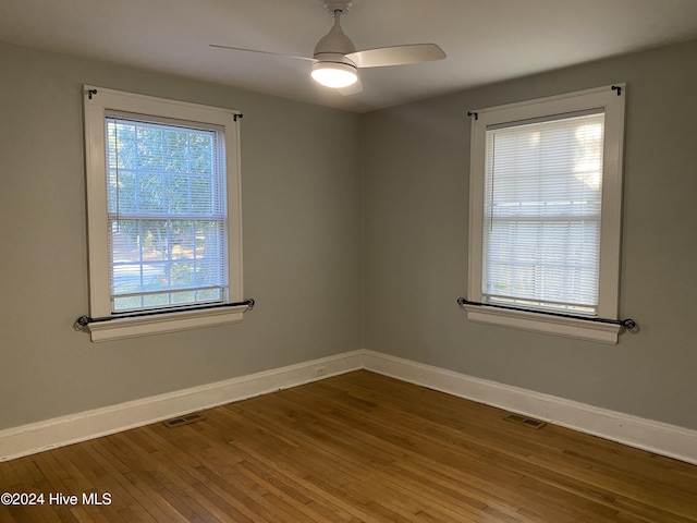 empty room with hardwood / wood-style flooring, ceiling fan, and a healthy amount of sunlight