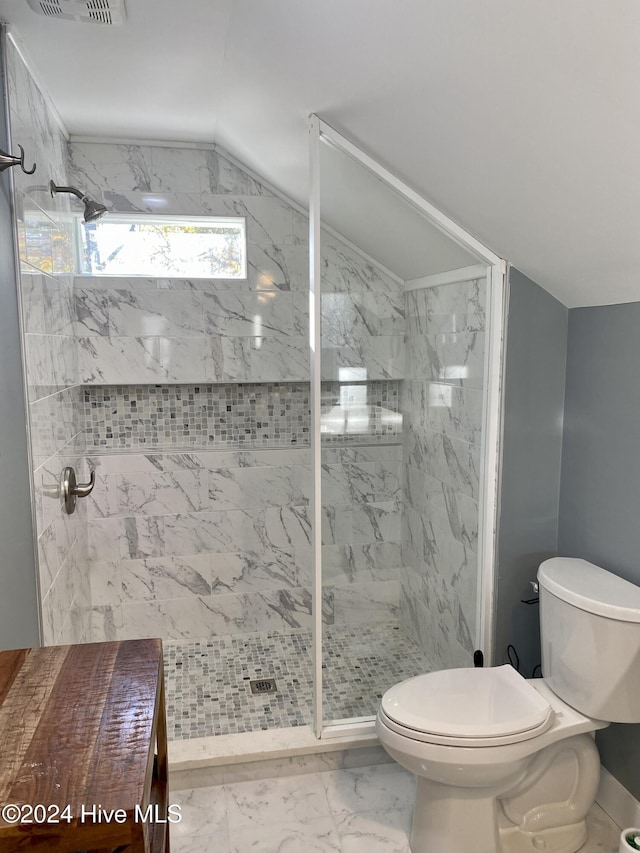 bathroom with a tile shower, toilet, and lofted ceiling