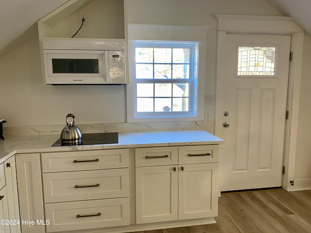 1121 Vance St N, Wilson, NC 27893 - kitchen featuring white microwave, healthy amount of natural light, black electric cooktop, light wood-style floors, and vaulted ceiling