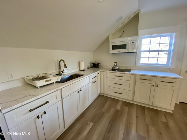 1121 Vance St N, Wilson, NC 27893 - kitchen featuring white microwave, vaulted ceiling, black electric stovetop, dark wood-type flooring, and white cabinetry