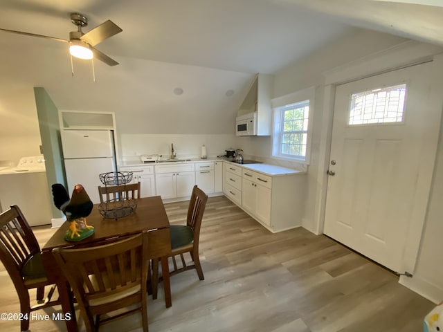 kitchen featuring washing machine and clothes dryer, white cabinets, vaulted ceiling, and white appliances