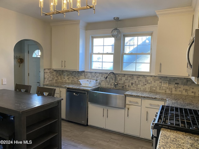 1121 Vance St N, Wilson, NC 27893 - kitchen with appliances with stainless steel finishes, tasteful backsplash, arched walkways, white cabinets, and hanging light fixtures