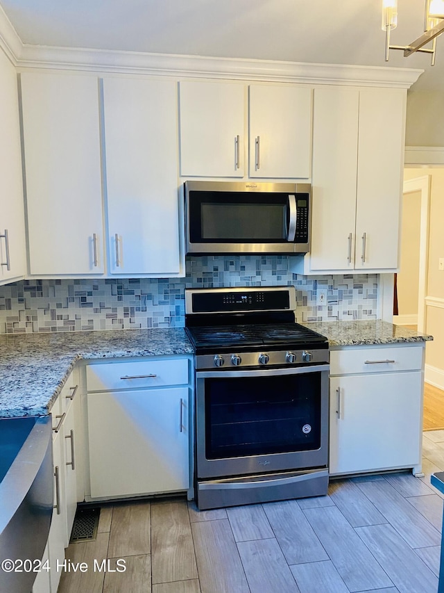 1121 Vance St N, Wilson, NC 27893 - kitchen with stainless steel appliances, wood tiled floors, white cabinetry, light stone countertops, and crown molding