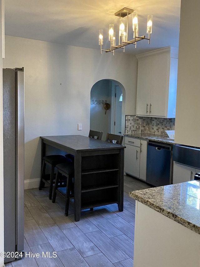 kitchen with tasteful backsplash, pendant lighting, light hardwood / wood-style floors, white cabinets, and appliances with stainless steel finishes