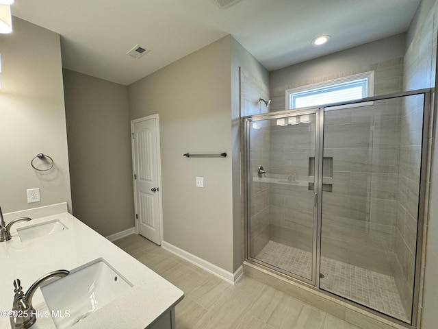 bathroom featuring double vanity, a stall shower, and a sink