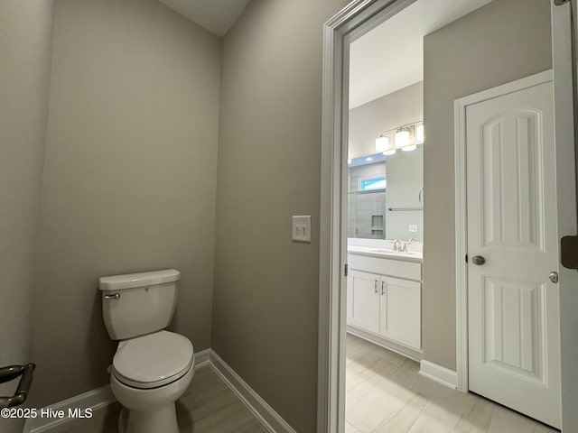 half bath with vanity, toilet, and baseboards