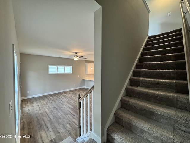 staircase with wood finished floors, baseboards, and ceiling fan