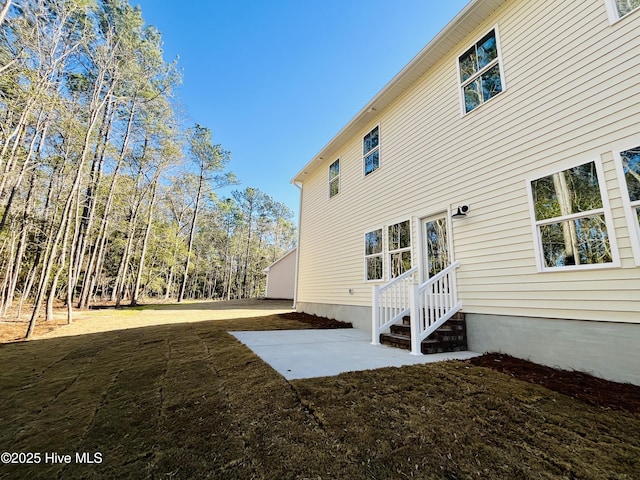 view of side of property featuring a lawn and a patio