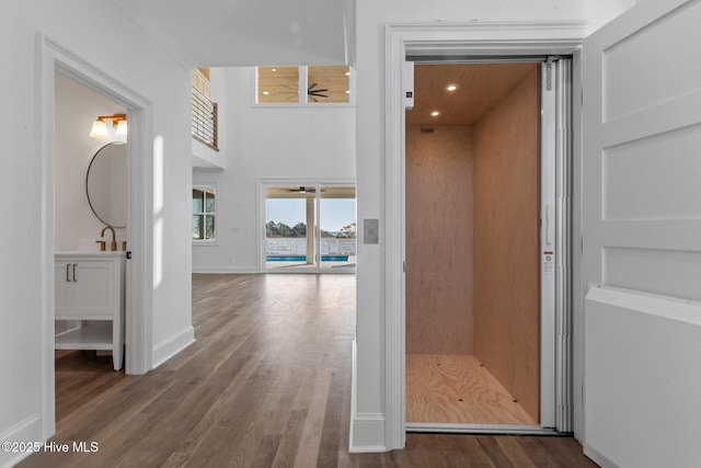 hall featuring a high ceiling, elevator, and hardwood / wood-style floors