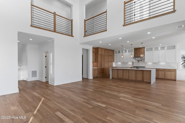 unfurnished living room with a high ceiling, hardwood / wood-style flooring, and sink