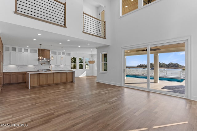 unfurnished living room with sink, hardwood / wood-style flooring, and a towering ceiling