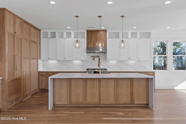 kitchen with a large island with sink, white cabinets, and light wood-type flooring