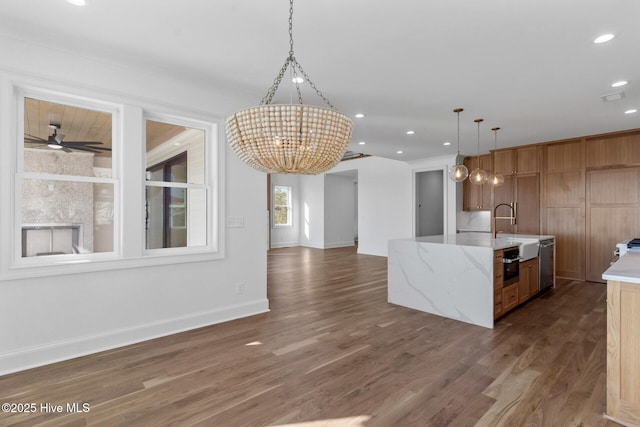 kitchen featuring dark hardwood / wood-style floors, pendant lighting, sink, stainless steel dishwasher, and a spacious island