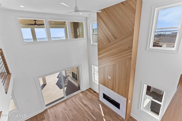 unfurnished living room featuring a wealth of natural light, ceiling fan, and light wood-type flooring