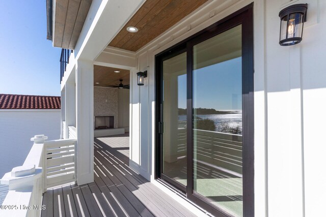 wooden terrace with a large fireplace and ceiling fan