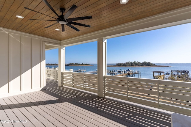 wooden deck with a water view and ceiling fan