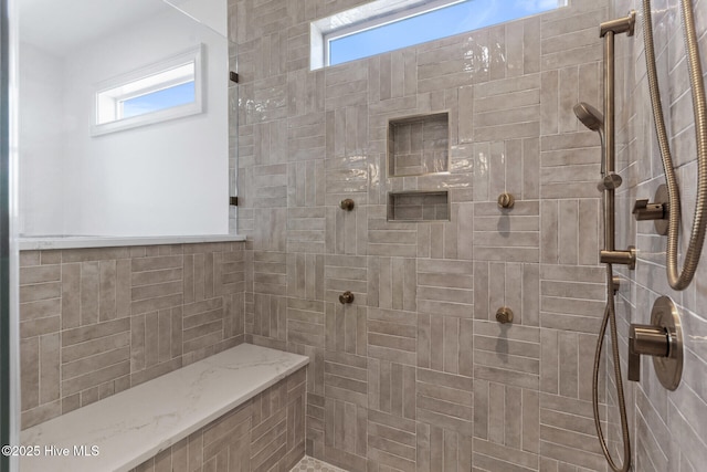 bathroom featuring tiled shower and a wealth of natural light