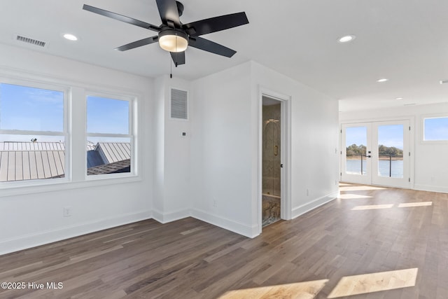 unfurnished room featuring dark wood-type flooring, french doors, ceiling fan, and a water view