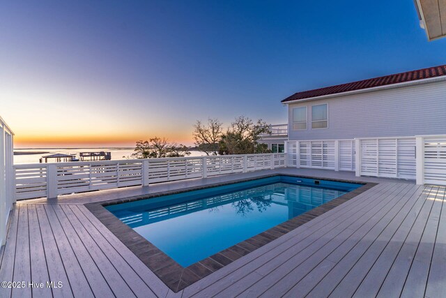 pool at dusk featuring a deck