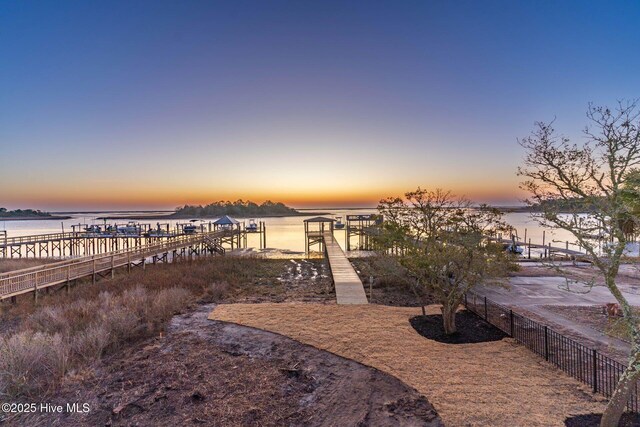 deck at dusk featuring a large fireplace, ceiling fan, and a water view