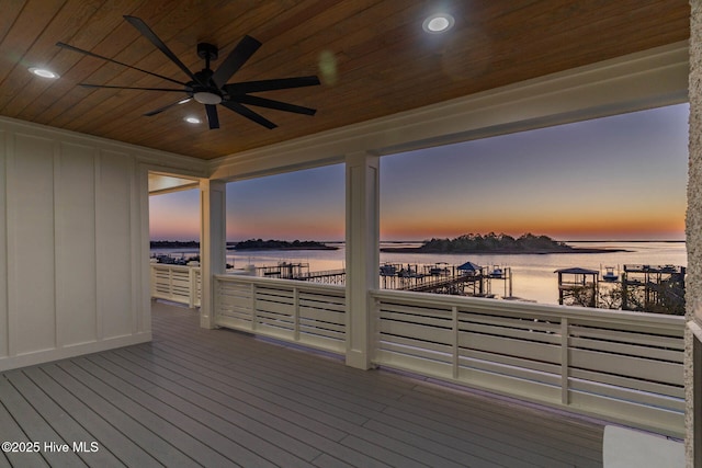 deck at dusk featuring a water view and ceiling fan