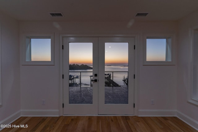 doorway to outside with hardwood / wood-style flooring, a water view, and french doors