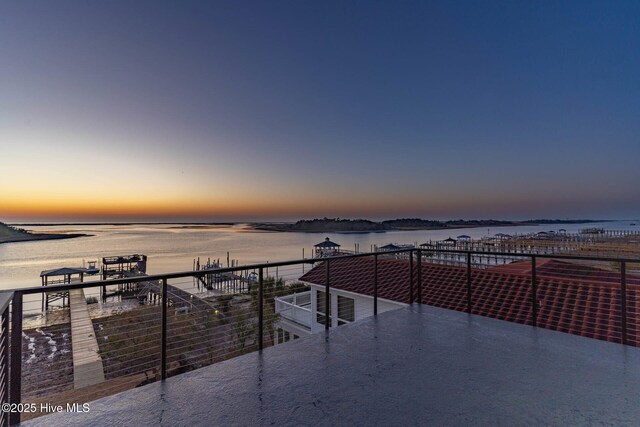 patio terrace at dusk featuring a water view