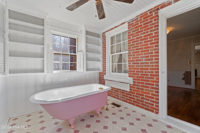 bathroom with ceiling fan, built in features, brick wall, crown molding, and a bathtub