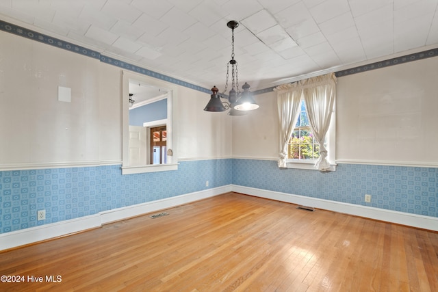 unfurnished dining area with hardwood / wood-style flooring, a notable chandelier, and crown molding