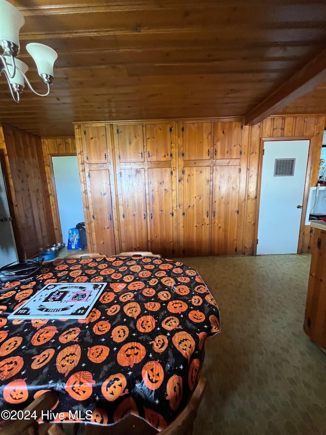 unfurnished bedroom with carpet, beam ceiling, wooden walls, and wood ceiling